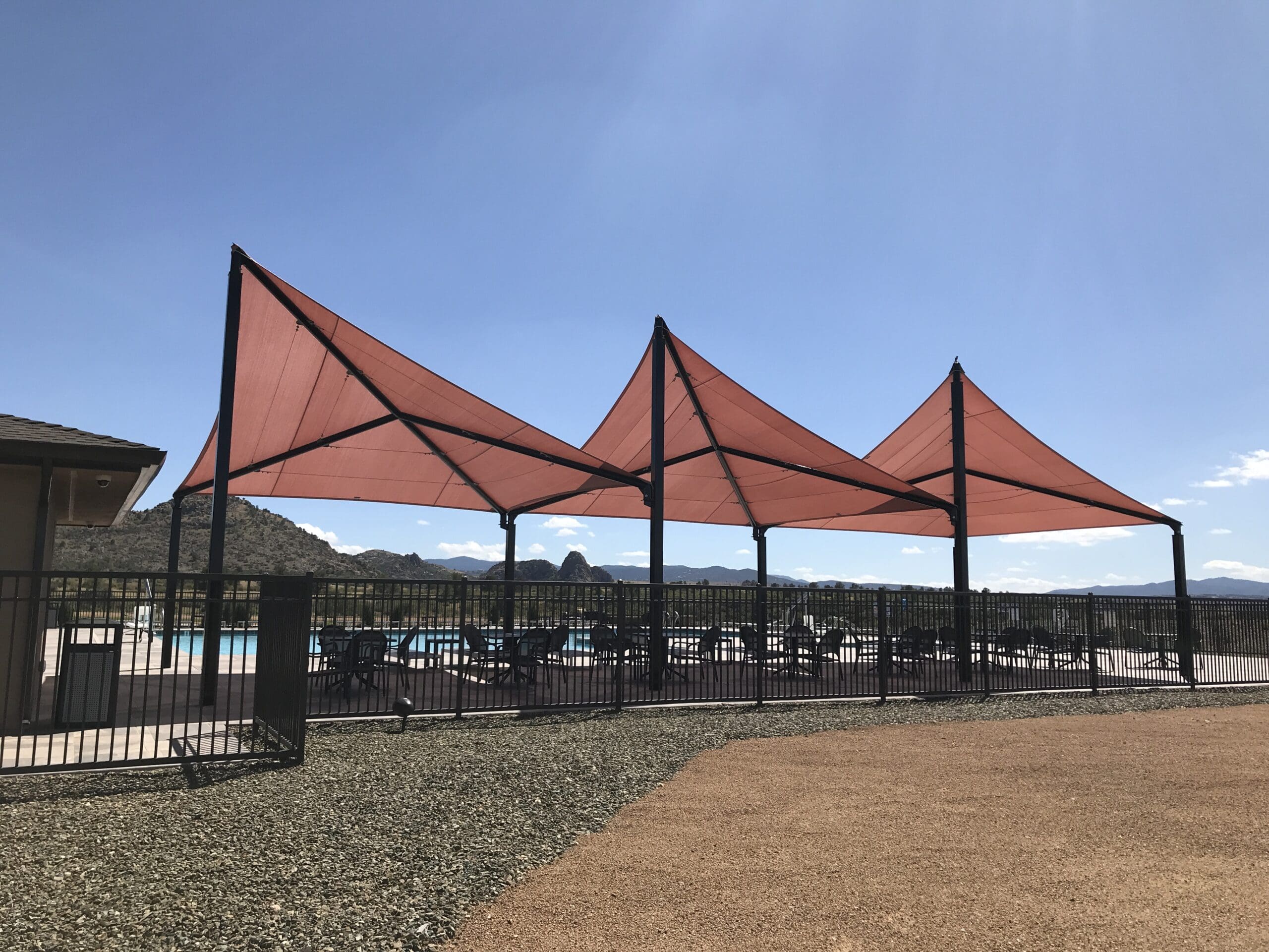 Fabric shade structure covering outdoor dining area next to pool at Granite Dells Estate Clubhouse in Prescott