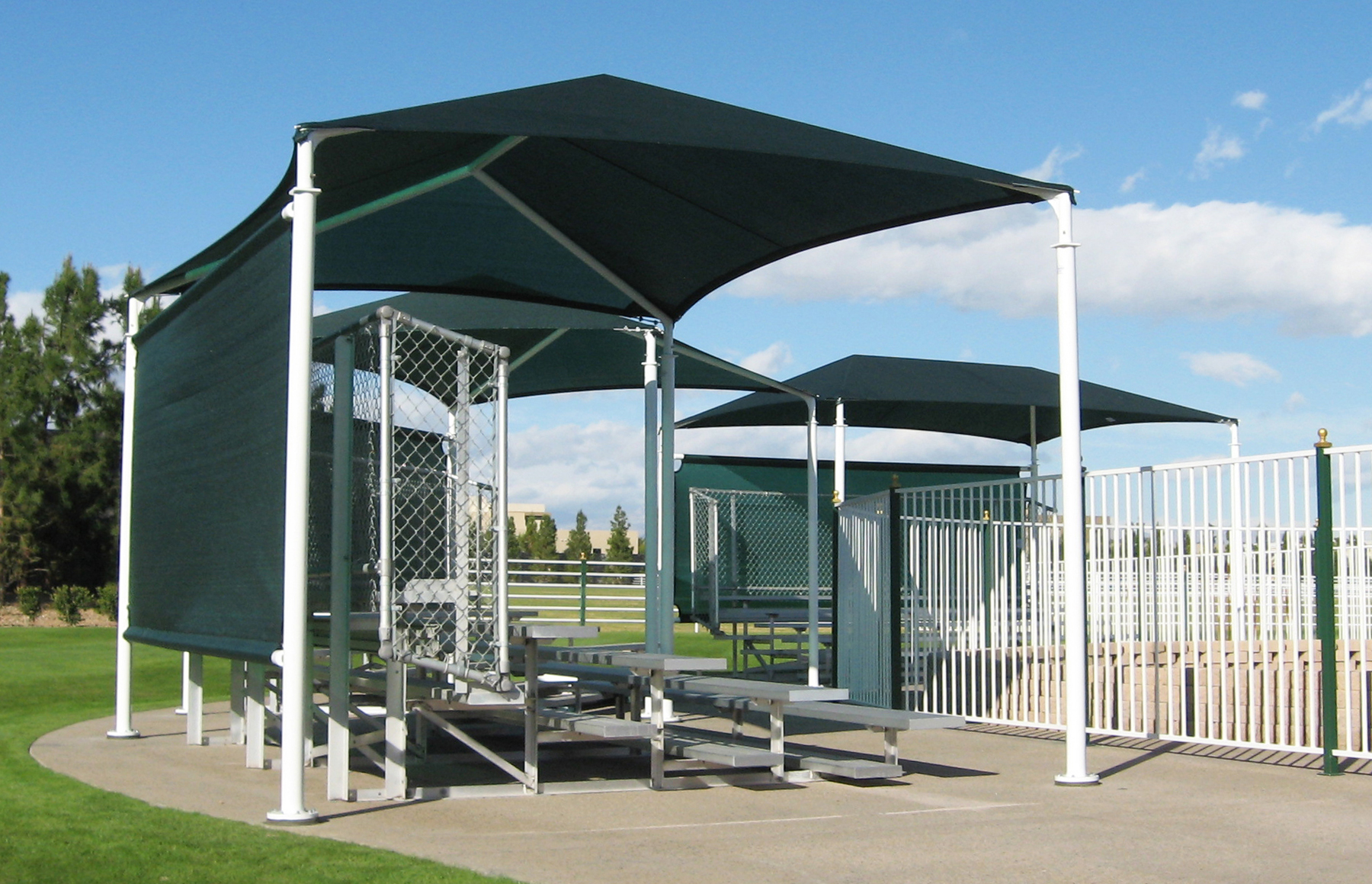 Hip and hip extended fabric shade structures covering bleachers next to the riding arena
