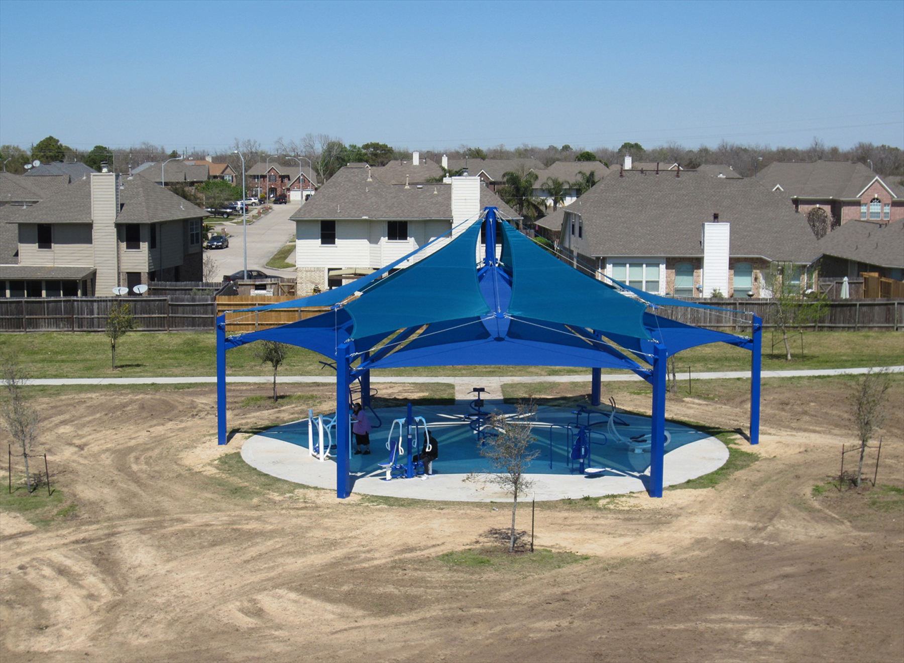 Large outdoor shade structure covering gym equipment at Eddie Huron Park