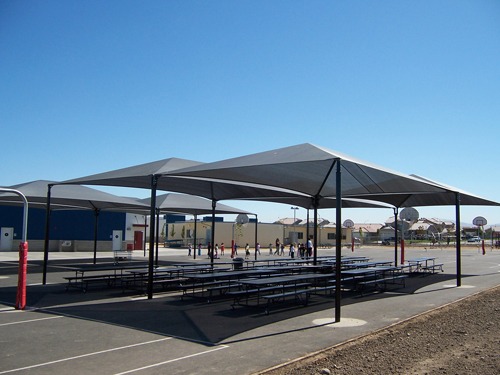 Outdoor eating area at George Kelly Elementary School covered by large shade structures for schools